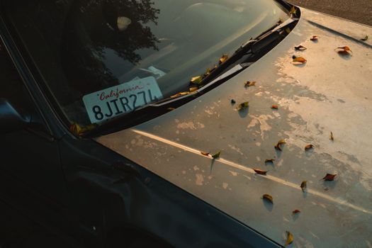 mot manuscrit avec nom, numéro de téléphone et immatriculation, glissé sous l'essuie-glace d'un véhicule accroché sur un parking