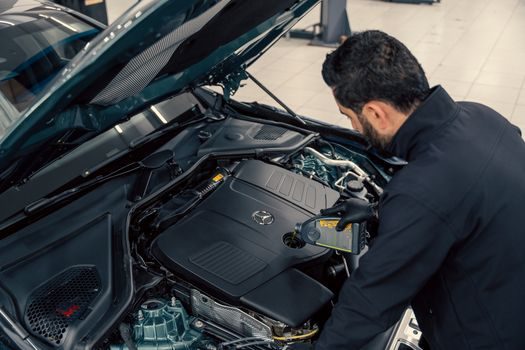 main gantée retirant le bouchon du vase d'expansion d'une Renault Clio 2, moteur ouvert, capot levé, vérification du niveau de liquide de refroidissement